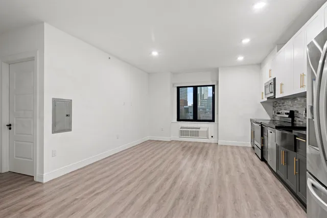 a view of an empty room with a window and wooden floor