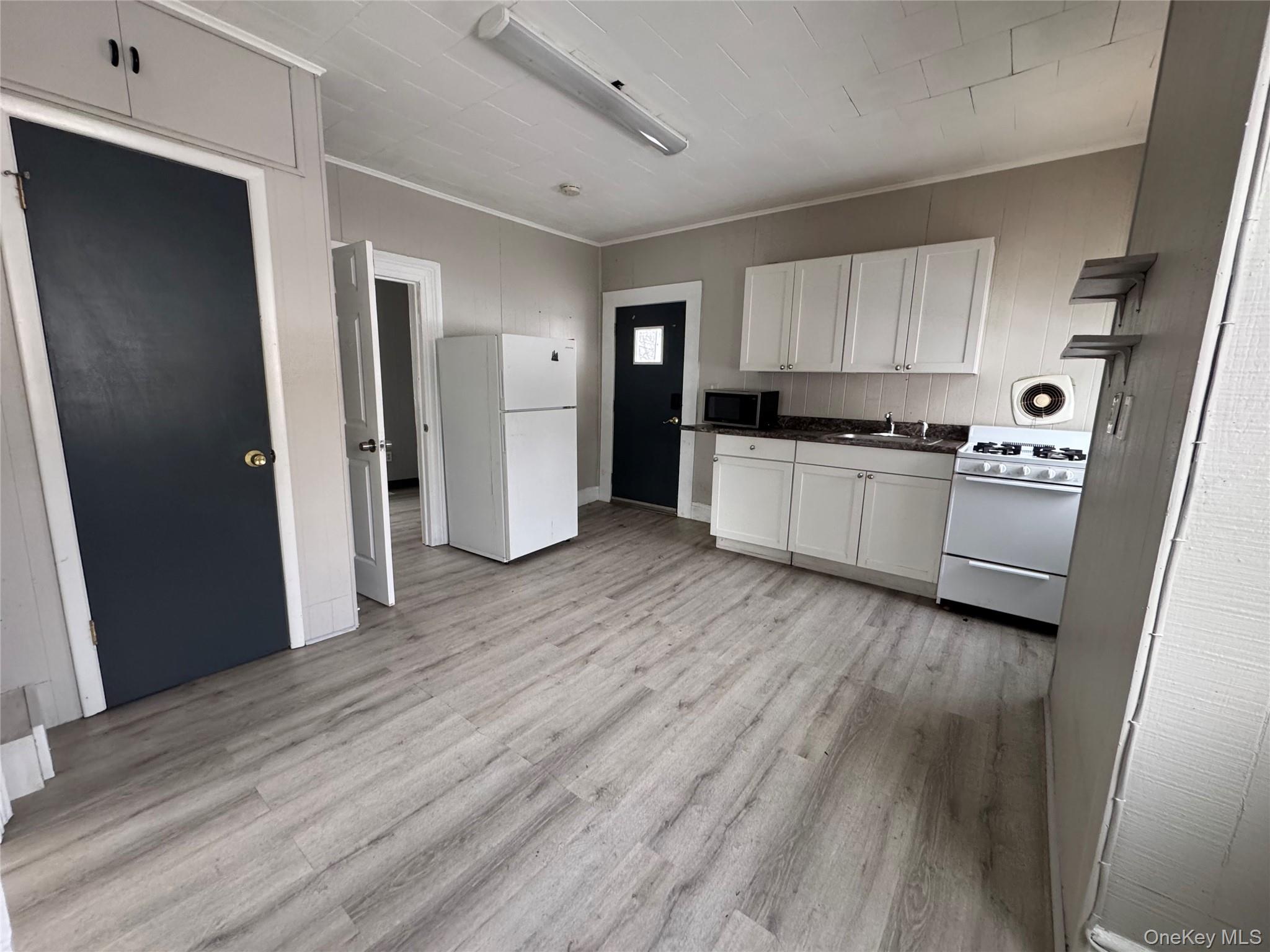 34 Hoffman Street Poughkeepsie, NY 12601 - Photo 3 of 10 a kitchen with a refrigerator a stove top oven and wooden floor