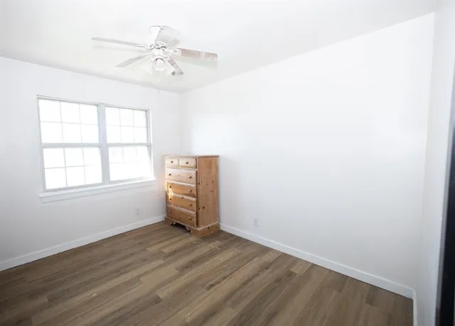 an empty room with a window and a ceiling fan