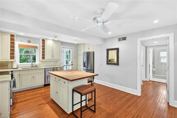 a kitchen with stainless steel appliances granite countertop wooden floors and white cabinets