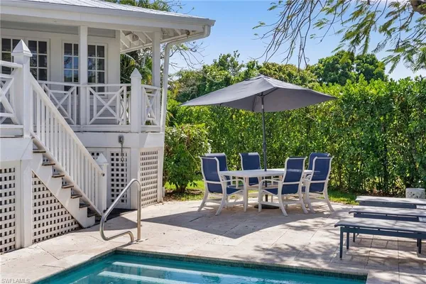 a view of a patio with couches table and chairs under an umbrella with a barbeque