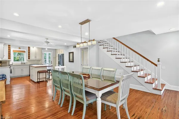 a dining room with wooden floor a chandelier a wooden table and chairs