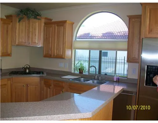 an open kitchen with granite countertop a stove a sink and dishwasher with wooden cabinets