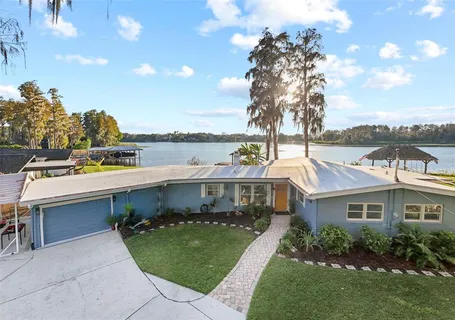 a front view of a house with a garden and lake view