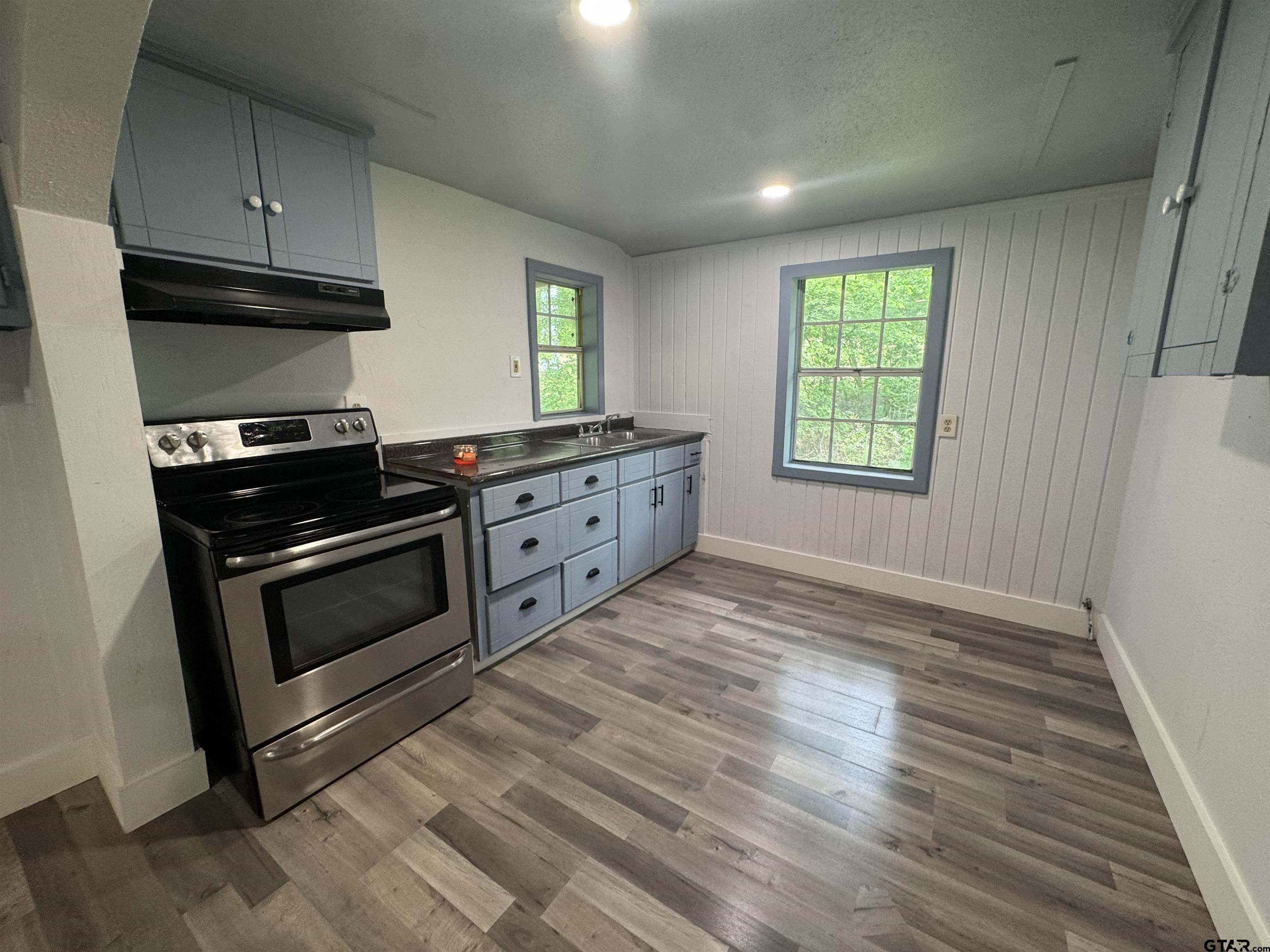 8124 County Road 381 Tyler, TX 75708 - Photo 20 of 23 a kitchen with granite countertop a stove a sink and a wooden floors