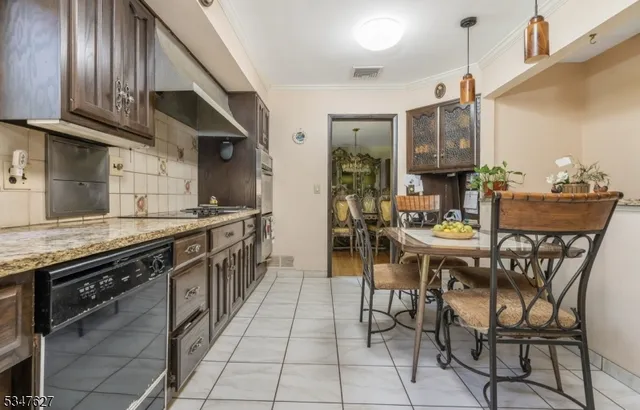 a kitchen with stainless steel appliances kitchen island granite countertop a table chairs sink and cabinets
