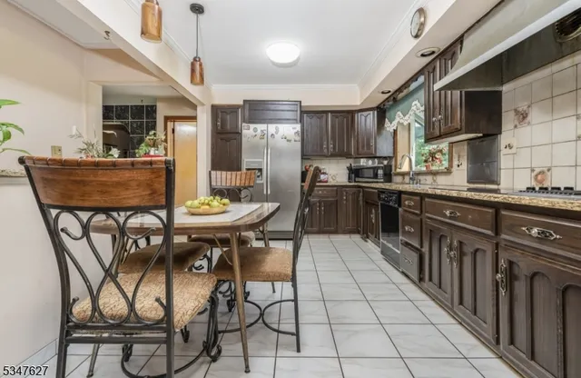 a kitchen with stainless steel appliances kitchen island granite countertop a sink a stove a table and chairs