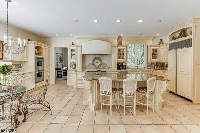 a kitchen with stainless steel appliances a stove a sink a oven a dining table and chairs