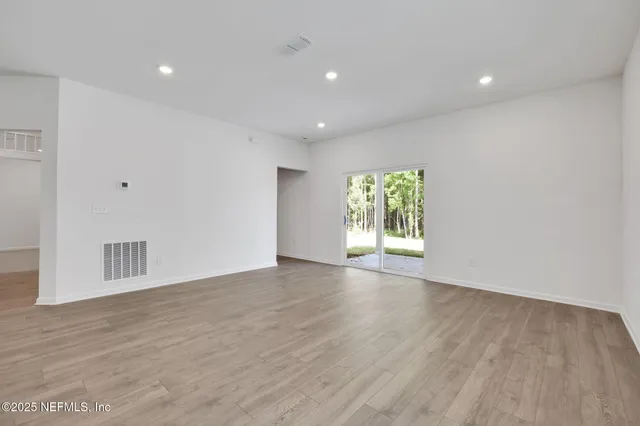 a view of an empty room with wooden floor and window