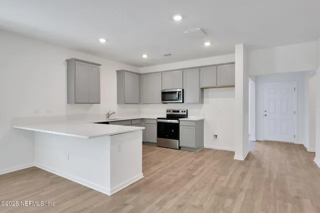 a kitchen with a refrigerator a stove top oven and white cabinets