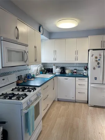 a kitchen with granite countertop white cabinets and white appliances