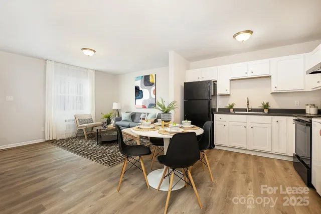 a kitchen with a table chairs a refrigerator and cabinets