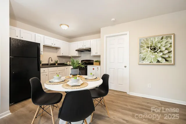 a kitchen with a refrigerator a stove a sink and a dining table with wooden floor