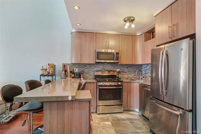 a kitchen with stainless steel appliances granite countertop a refrigerator a stove a sink and a microwave