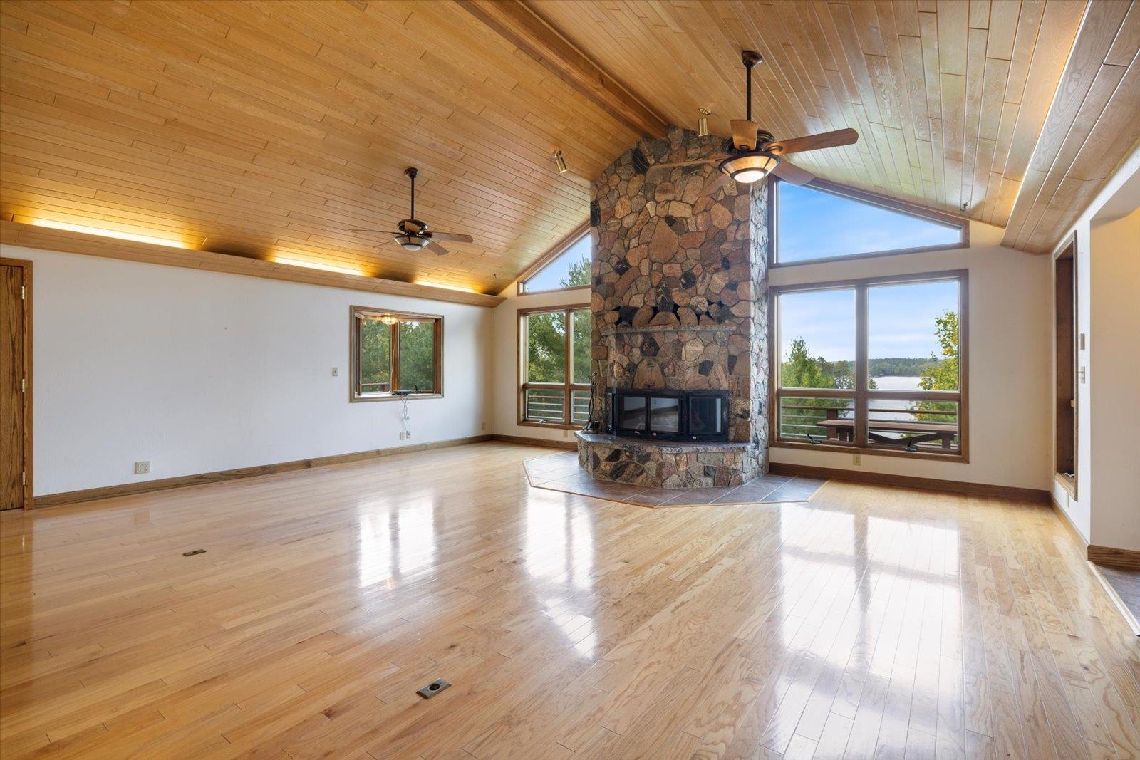 2375 Viste Point Road Ely, MN 55731 - Photo 17 of 83 Living room with light wood floors, stone fireplace, healthy amount of natural light, high vaulted ceiling, and wood ceiling