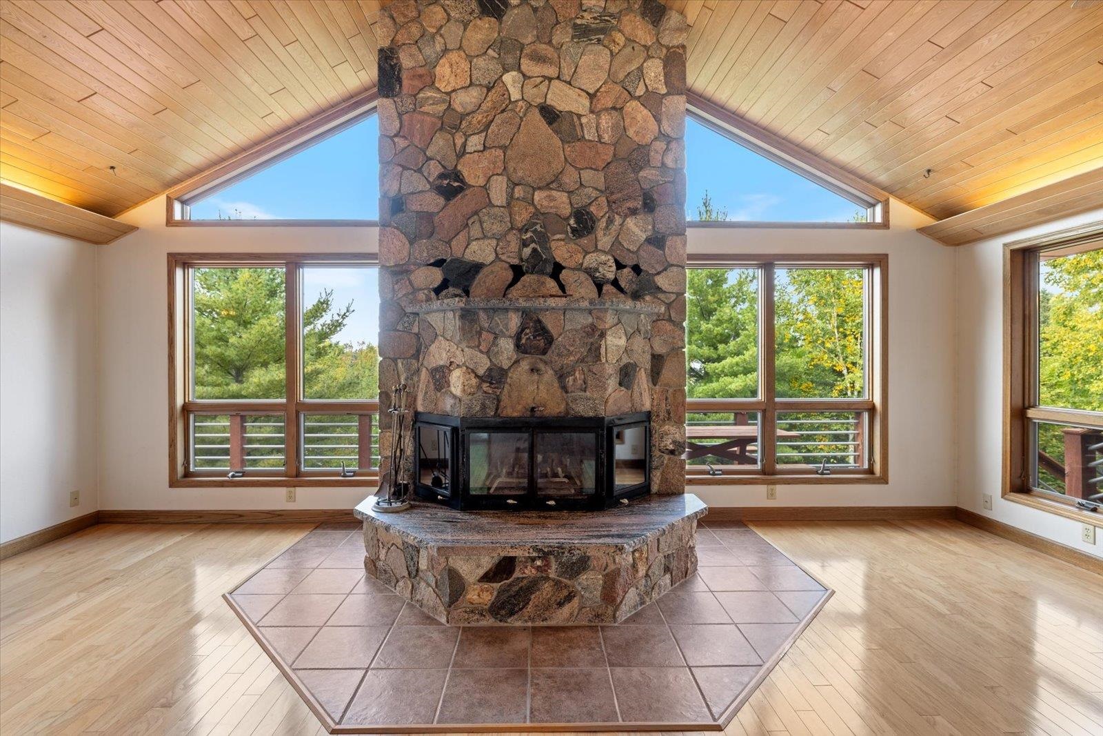 2375 Viste Point Road Ely, MN 55731 - Photo 18 of 83 Living room with light wood floors, stone fireplace, healthy amount of natural light, high vaulted ceiling, and wood ceiling