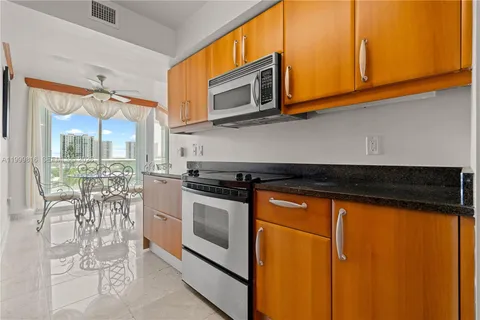 a kitchen with stainless steel appliances granite countertop a stove a microwave and a view of living room