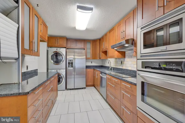 a kitchen with stainless steel appliances granite countertop a stove a sink and a refrigerator