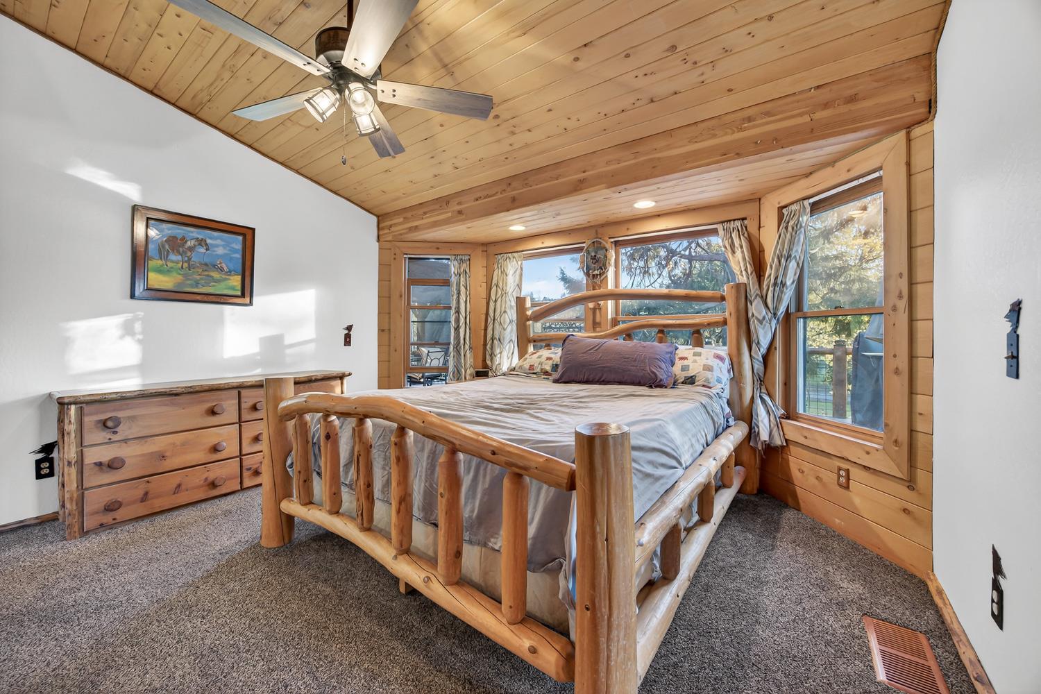 10394 Ponderosa Way Mountain Ranch, CA 95246 - Photo 18 of 58 a bedroom with a large bed and a chandelier
