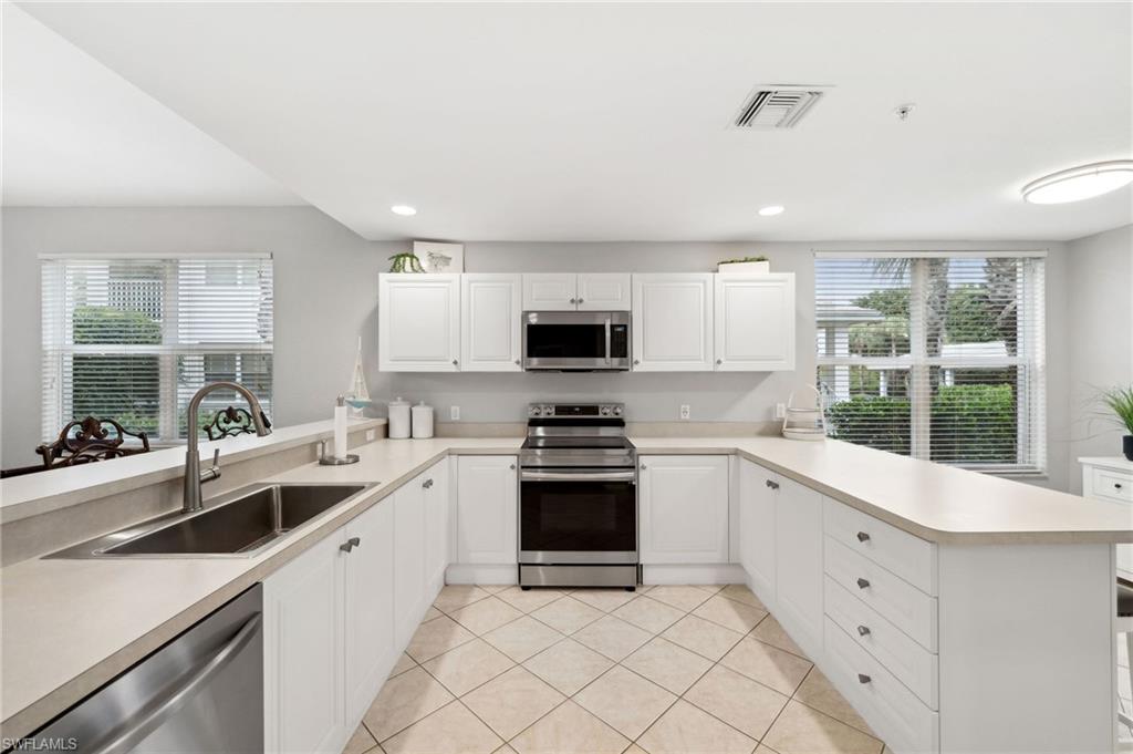 8355 Whisper Trace Lane, Unit K104 Naples, FL 34114 - Photo 6 of 21 a kitchen with white cabinets and appliances