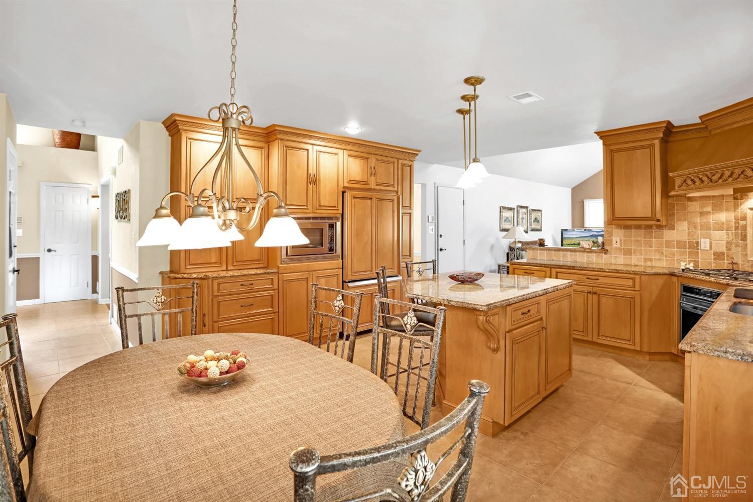 2 Astor Drive Manalapan, NJ 07726 - Photo 27 of 60 a kitchen with stainless steel appliances a stove a sink a chimney a dining table and chairs