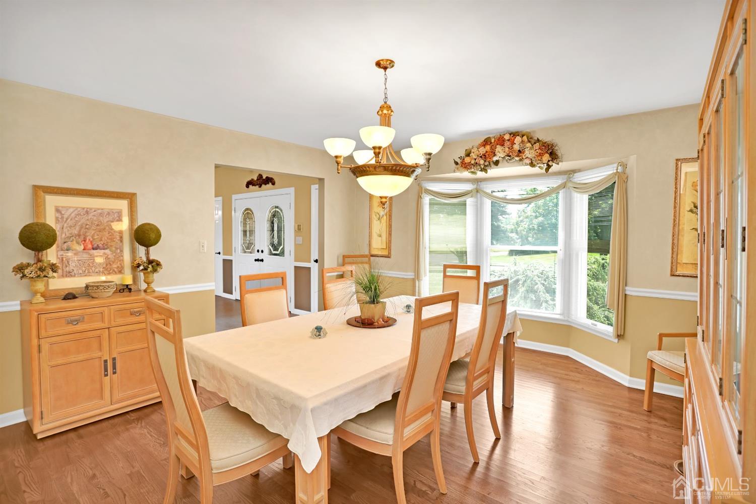2 Astor Drive Manalapan, NJ 07726 - Photo 31 of 60 a dining room with wooden floor a chandelier a wooden table and chairs