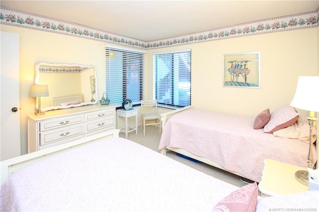 4540 Northeast Sandpebble Trace, Unit 105 Stuart, FL 34996 - Photo 20 of 39 a spacious bedroom with a bed a couch and a window