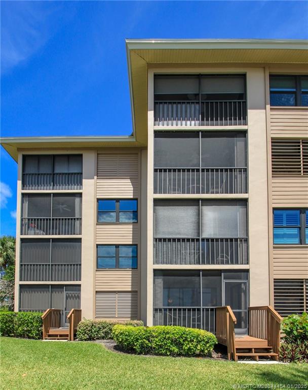 4540 Northeast Sandpebble Trace, Unit 105 Stuart, FL 34996 - Photo 27 of 39 a front view of a house with a yard