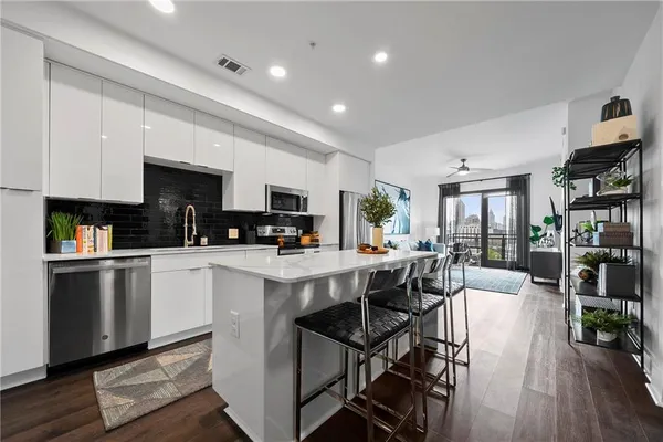 a kitchen with stainless steel appliances granite countertop a table chairs refrigerator and sink