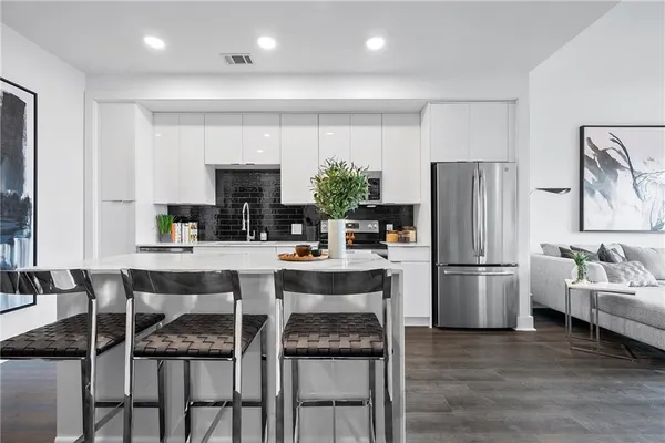 a kitchen with refrigerator a oven and chairs