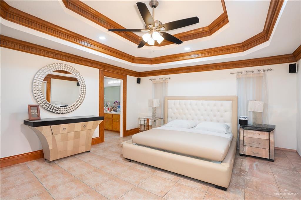 1701 Raul Aguilar Drive Mission, TX 78572 - Photo 13 of 43 a spacious bedroom with a bed a mirror and a chandelier