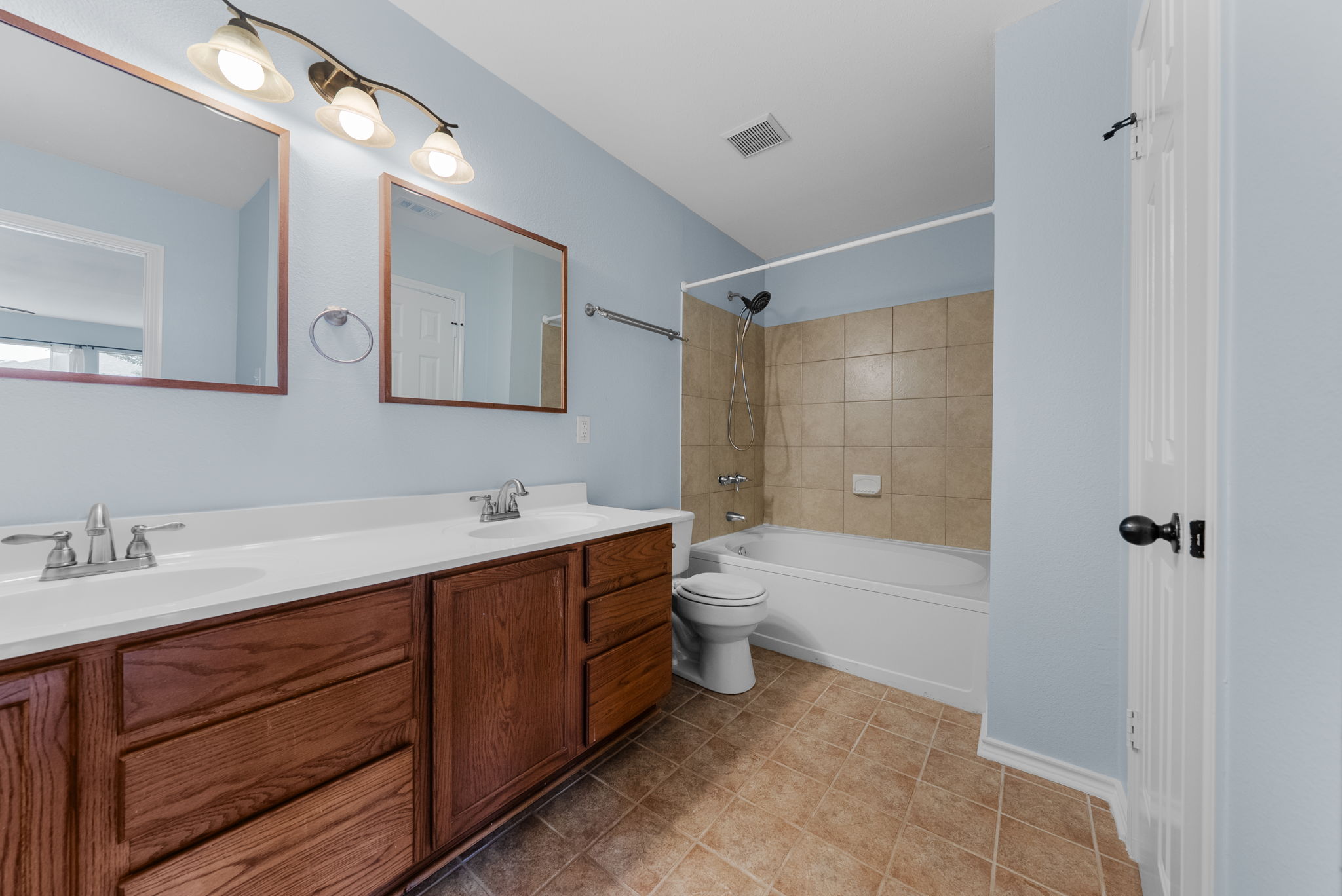 7327 Pusch Ridge Loop Austin, TX 78749 - Photo 21 of 26 A well-appointed bathroom features a double vanity and a combined shower-tub unit, offering both convenience and practicality.