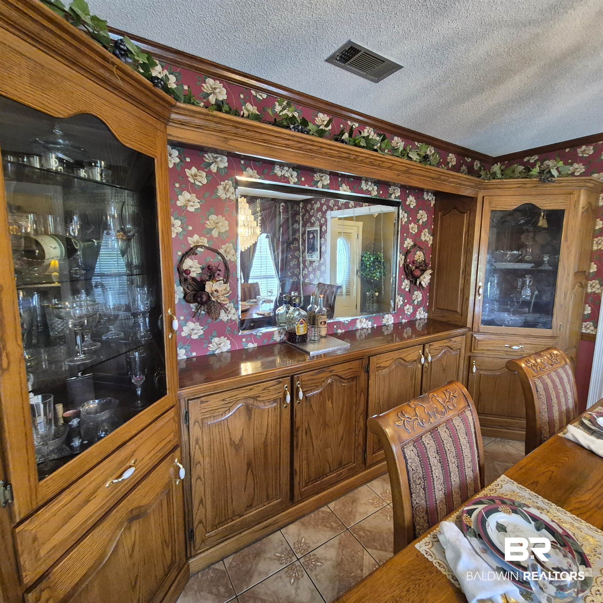 26635 Highway 41 Range, AL 36473 - Photo 19 of 74 Bar area with dark countertops, a textured ceiling, wood finish cabinetry, wallpapered walls, and light tile patterned floors