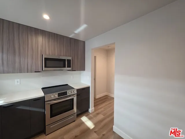 a kitchen with stainless steel appliances a stove a microwave and a hard wood floor