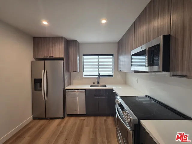 a kitchen with granite countertop stainless steel appliances a sink stove and refrigerator