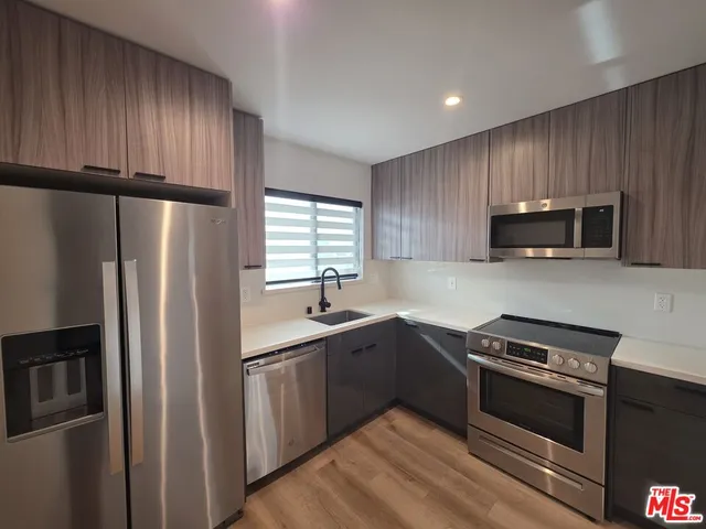 a kitchen with stainless steel appliances granite countertop a refrigerator stove a sink dishwasher and microwave