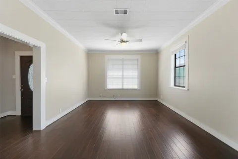 an empty room with wooden floor chandelier and windows