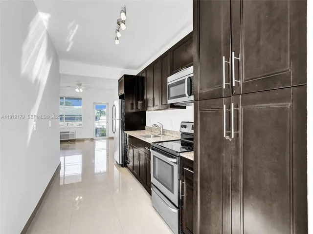 a kitchen with stainless steel appliances granite countertop a refrigerator a stove and a sink