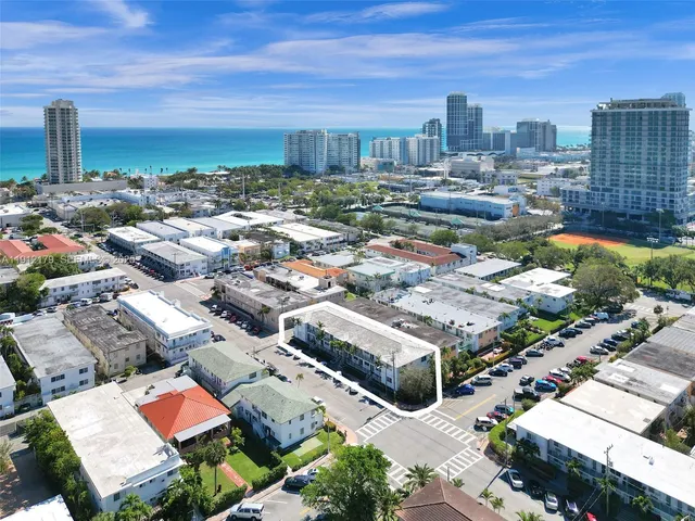 an aerial view of a city with lots of residential buildings and ocean view in back
