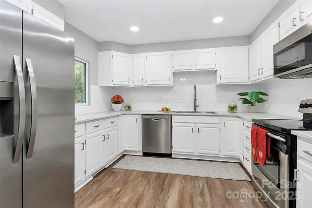 a kitchen with stainless steel appliances granite countertop a sink a stove a refrigerator and cabinets