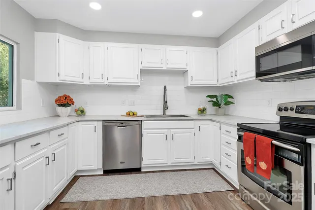 a kitchen with stainless steel appliances white cabinets sink and wooden floor