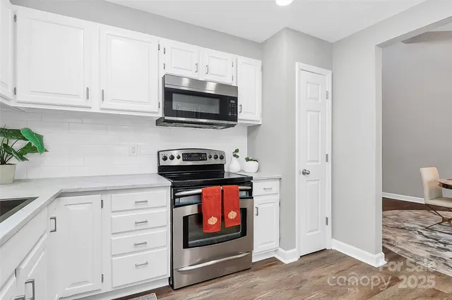 a kitchen with stainless steel appliances white cabinets and stove top oven