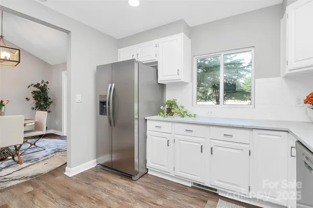 a kitchen with white cabinets and wooden floor