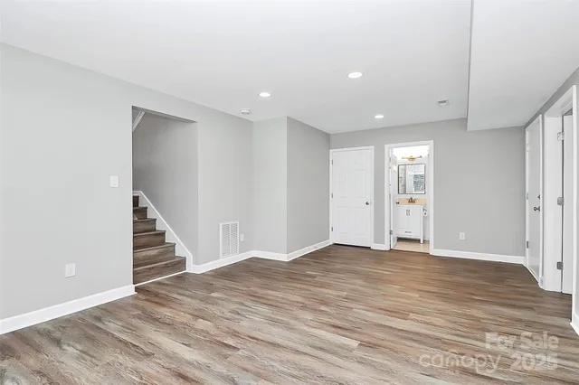 a view of an empty room with wooden floor and stairs