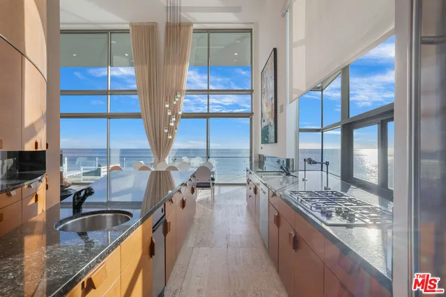 a kitchen with stainless steel appliances granite countertop a sink a stove and a wooden floor