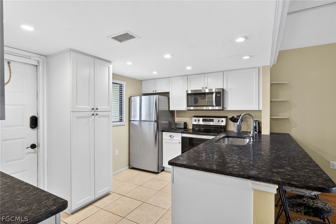 1251 Barrett Road, Unit 702 North Fort Myers, FL 33903 - Photo 3 of 30 a kitchen with a refrigerator a microwave a stove and white cabinets with wooden floor