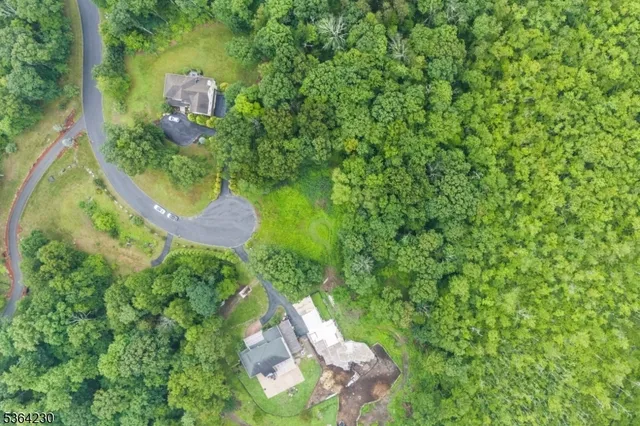 an aerial view of residential house with outdoor space and trees all around