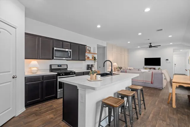 a kitchen with stainless steel appliances kitchen island granite countertop a sink stove and refrigerator
