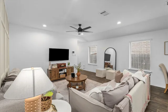 a kitchen with stainless steel appliances granite countertop a stove top oven a sink a refrigerator a dining table and chairs with wooden floor