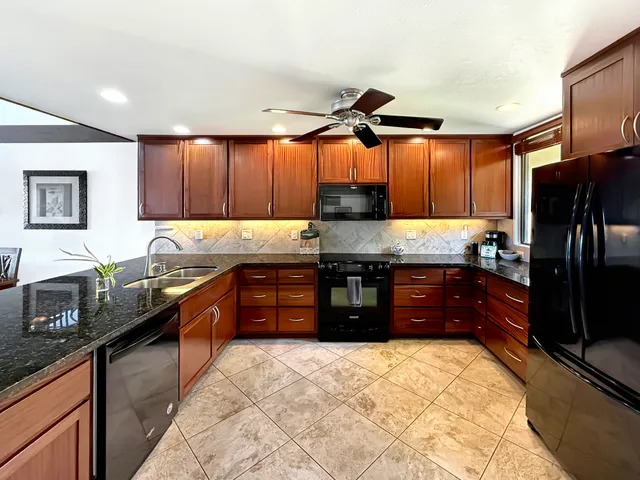 a kitchen with granite countertop a refrigerator and a stove top oven